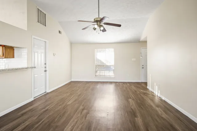 an empty room with wooden floor and windows