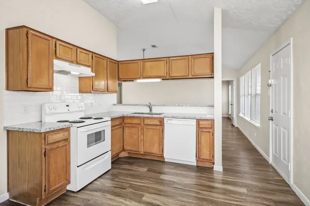 a kitchen with granite countertop wooden cabinets and white appliances