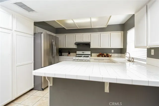 a kitchen with kitchen island a sink a stove a refrigerator and cabinets
