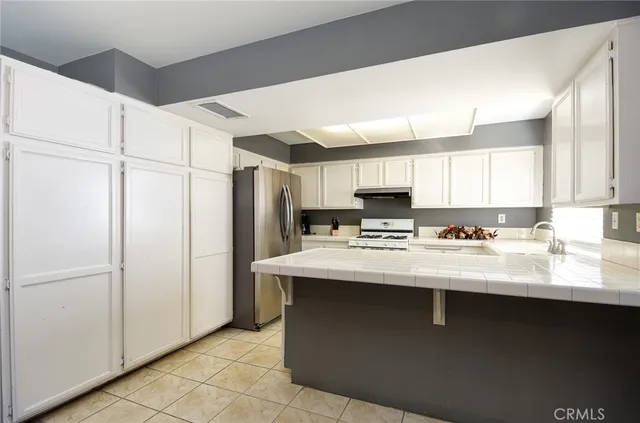 a kitchen with stainless steel appliances granite countertop a sink a refrigerator and a stove