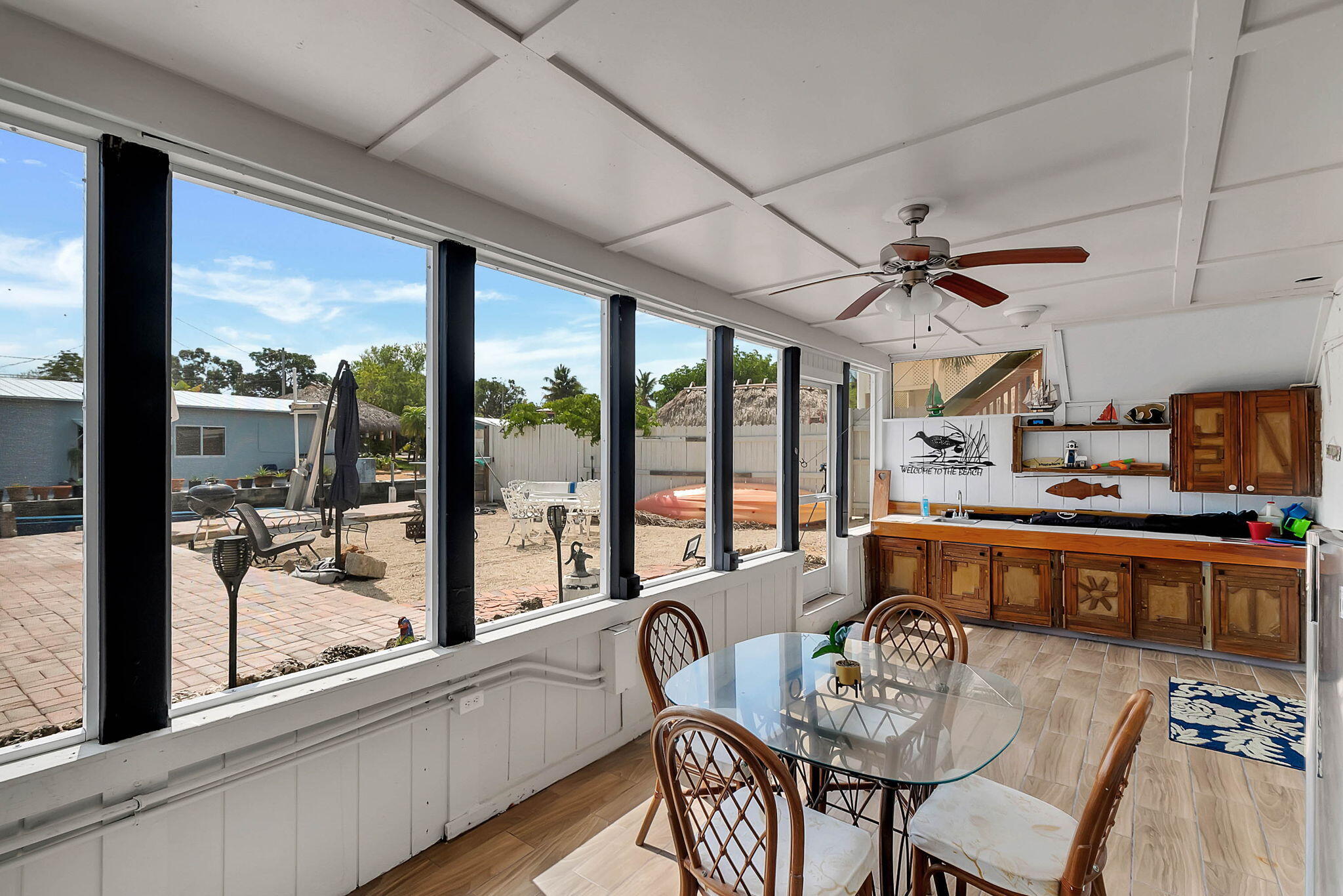 108 Long Ben Drive Key Largo, FL 33037 - Photo 37 of 43 a dining room with wooden floor a chandelier fan a glass table and chairs