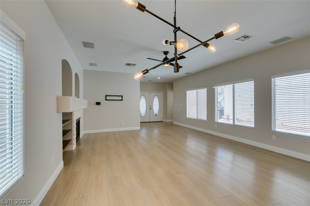 8909 Houston Ridge Avenue Las Vegas, NV 89178 - Photo 11 of 45 Blonde hardwood floors extend through this ample living area with a modern chandelier and inviting fireplace.