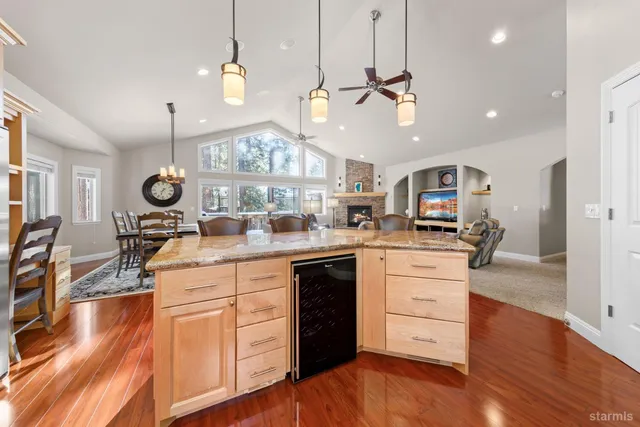 a kitchen with stainless steel appliances kitchen island granite countertop a stove a sink and white cabinets with wooden floor