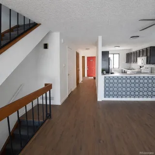 a view of a hallway to a livingroom with wooden floor and windows