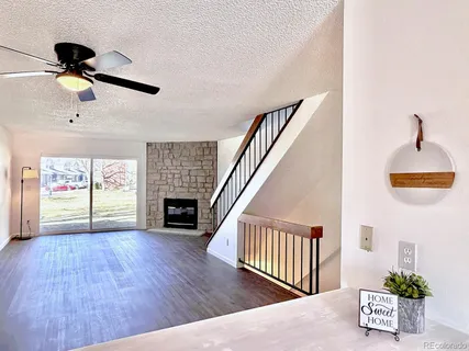 a view of an empty room with wooden floor fireplace and a window
