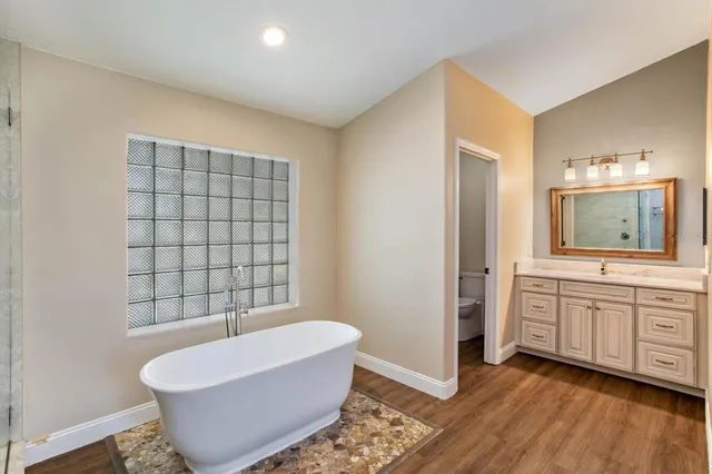 a view of an empty room with wooden floor and windows