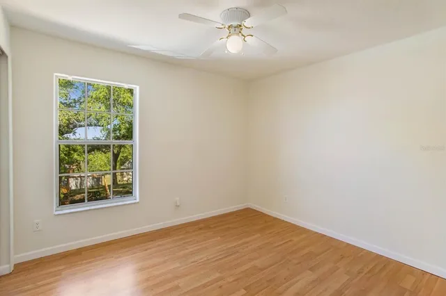 a view of empty room with wooden floor and fan