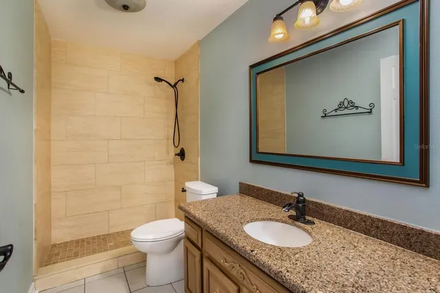 a bathroom with a granite countertop sink toilet a shower and a mirror