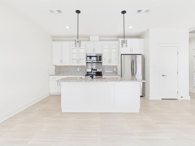 511 Richardson Street Athens, TX 75751 - Photo 6 of 40 Kitchen with white cabinets, pendant lighting, light stone counters, tasteful backsplash, and appliances with stainless steel finishes