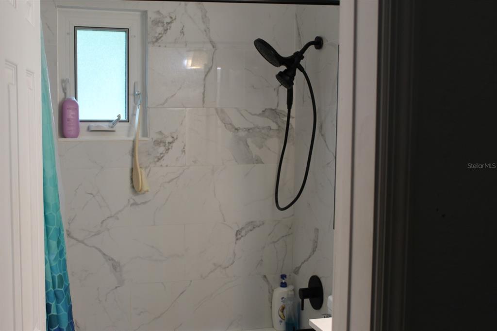 4928 Lake Ridge Lane Holiday, FL 34690 - Photo 6 of 7 a bathroom with a glass shower door