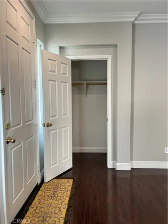 a view of a hallway with wooden floor and closet area
