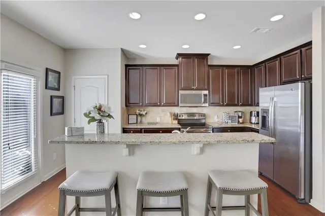 a kitchen with stainless steel appliances granite countertop a table chairs sink refrigerator and microwave