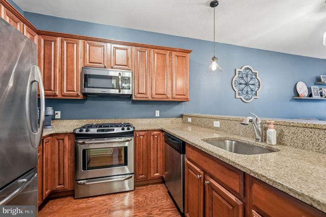 a kitchen with stainless steel appliances granite countertop a sink a stove a microwave oven with cabinets and wooden floor