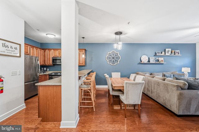 a living room with furniture a refrigerator and a kitchen view