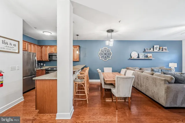 a living room with furniture a refrigerator and a kitchen view