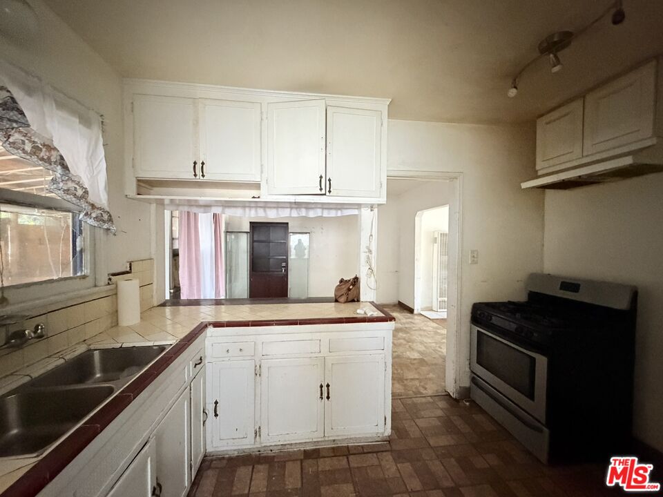 12918 Shreve Road Whittier, CA 90602 - Photo 33 of 42 a kitchen with granite countertop white cabinets and black appliances