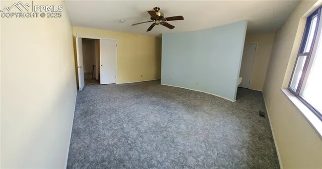 an empty room with windows and fan