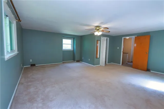 an empty room with windows and fan