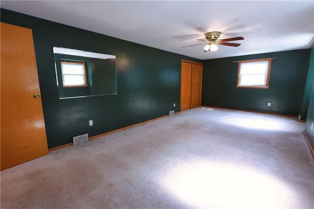 an empty room with windows and ceiling fan