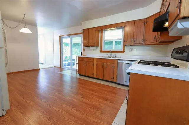 a kitchen with stainless steel appliances granite countertop wooden cabinets a stove a sink and a window