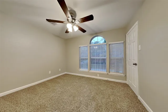 an empty room with windows and fan