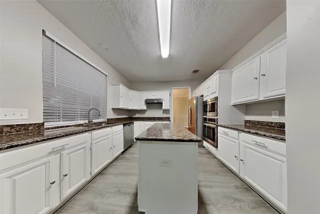 a large kitchen with cabinets wooden floor and stainless steel appliances