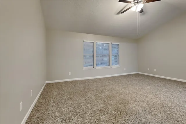 an empty room with a ceiling fan and window