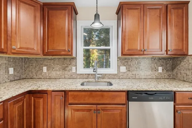 a kitchen with stainless steel appliances granite countertop a sink a stove a refrigerator cabinets and wooden floor