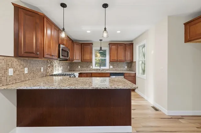 a kitchen with stainless steel appliances granite countertop wooden cabinets a stove top oven a sink and dishwasher