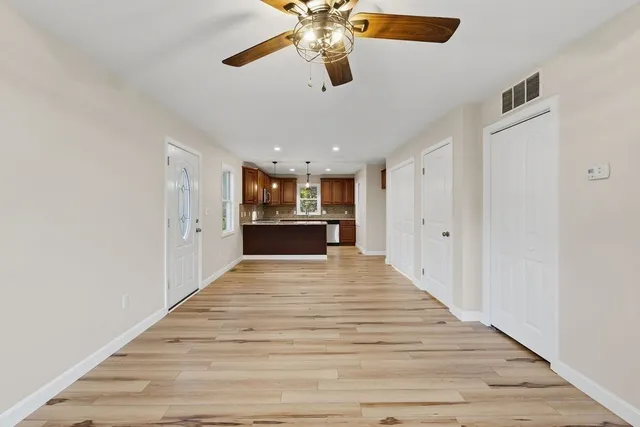 a view of a room with wooden floor ceiling fan and window