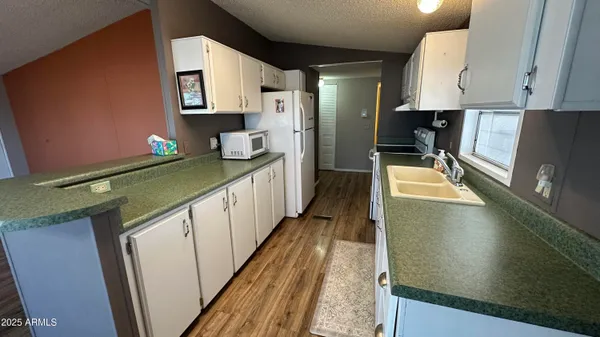 a kitchen with stainless steel appliances granite countertop a sink and cabinets with wooden floor
