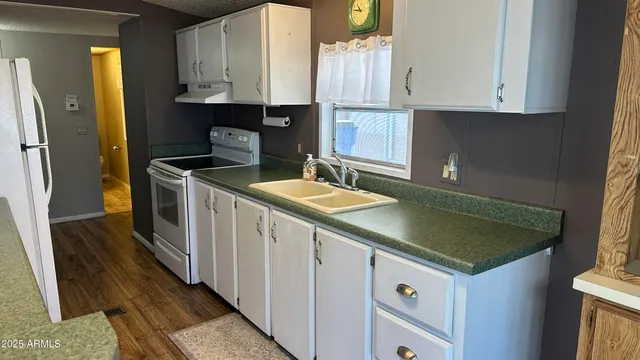 a kitchen with granite countertop a sink a stove and cabinets