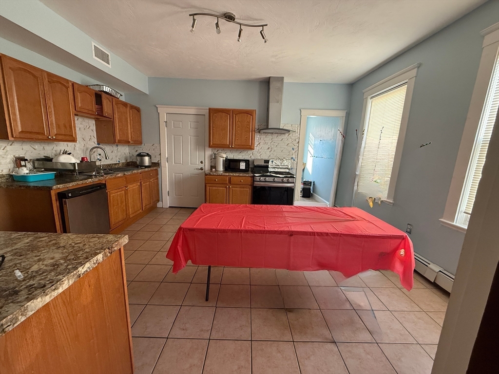 55 Lithgow Street, Unit 3 Boston, MA 02124 - Photo 2 of 16 a kitchen with stainless steel appliances kitchen island granite countertop a sink dishwasher stove and cabinets