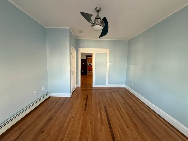 a view of empty room with wooden floor and fan