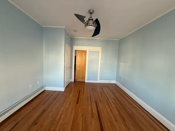 a view of empty room with wooden floor and fan