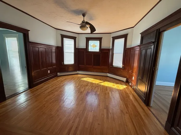 a view of empty room with wooden floor and fan