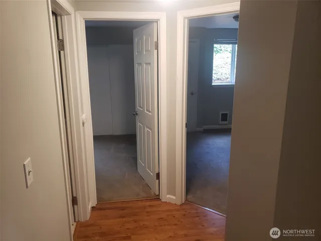 a view of a hallway with wooden floor and closet