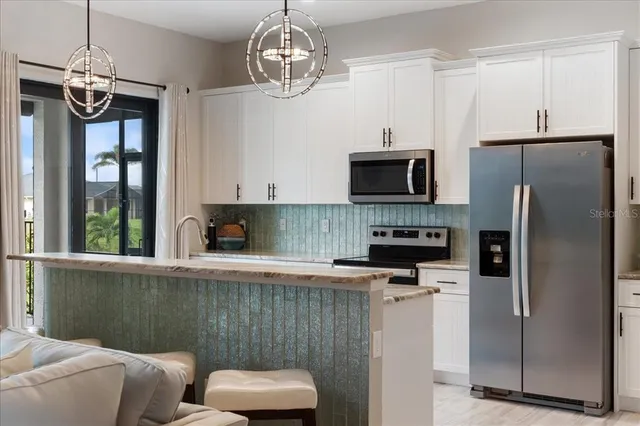 a large kitchen with stainless steel appliances granite countertop a stove top oven a sink dishwasher a dining table and chairs with wooden floor