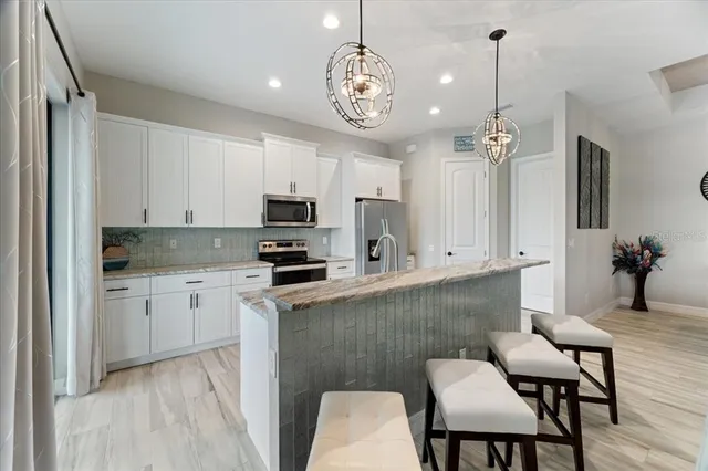 a kitchen with stainless steel appliances kitchen island granite countertop a refrigerator a stove a sink dishwasher a dining table and chairs with wooden floor