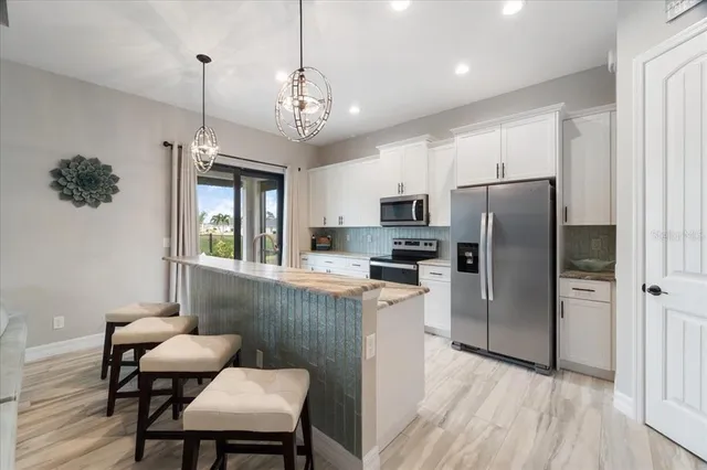 a large kitchen with kitchen island a dining table chairs and a wooden floor