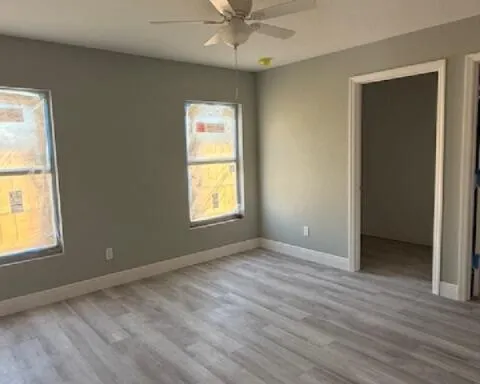 an empty room with windows and fan