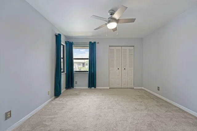 an empty room with windows and fan