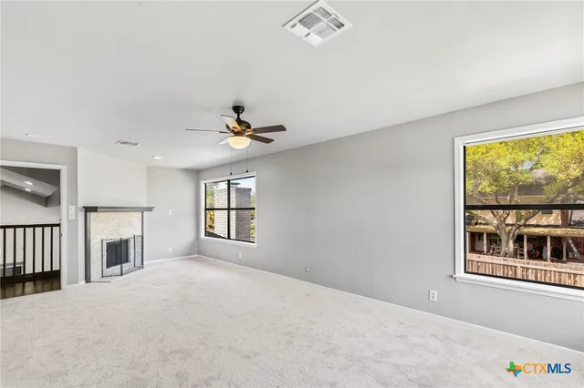 a view of an empty room with a window and fireplace