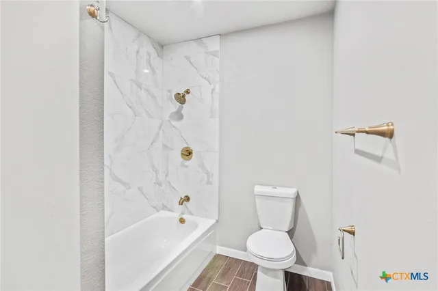 a white toilet sitting next to a bath tub and a shower