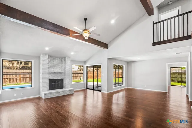 an empty room with fireplace wooden floor and windows