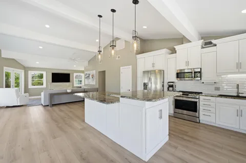 a kitchen with stainless steel appliances kitchen island granite countertop a stove top oven a sink a center island and cabinets