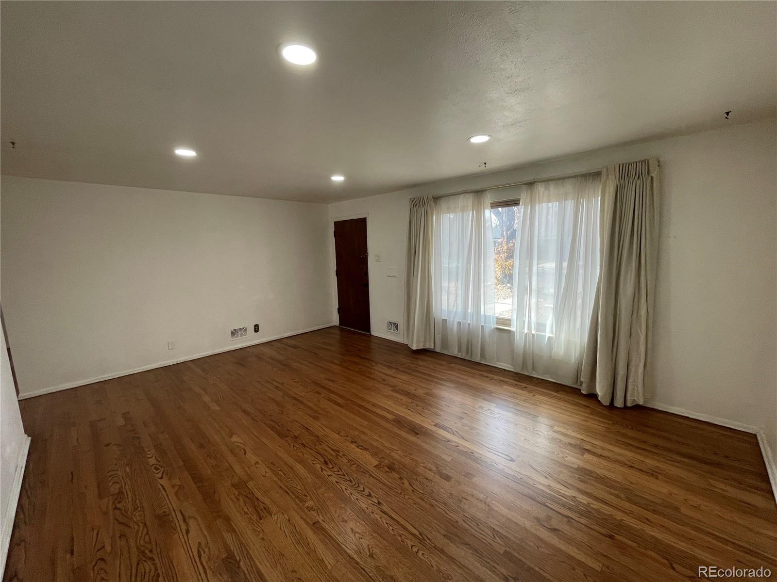 3086 Victor Street Aurora, CO 80011 - Photo 4 of 30 an empty room with wooden floor and windows