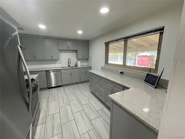 a kitchen with stainless steel appliances granite countertop refrigerator sink and wooden cabinets