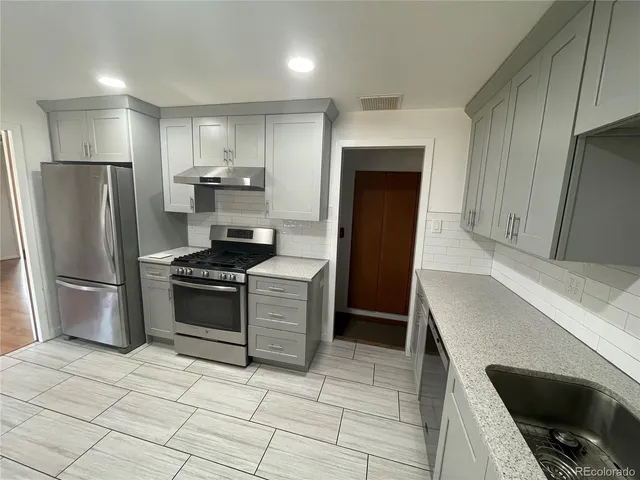 a kitchen with granite countertop a refrigerator and a stove top oven