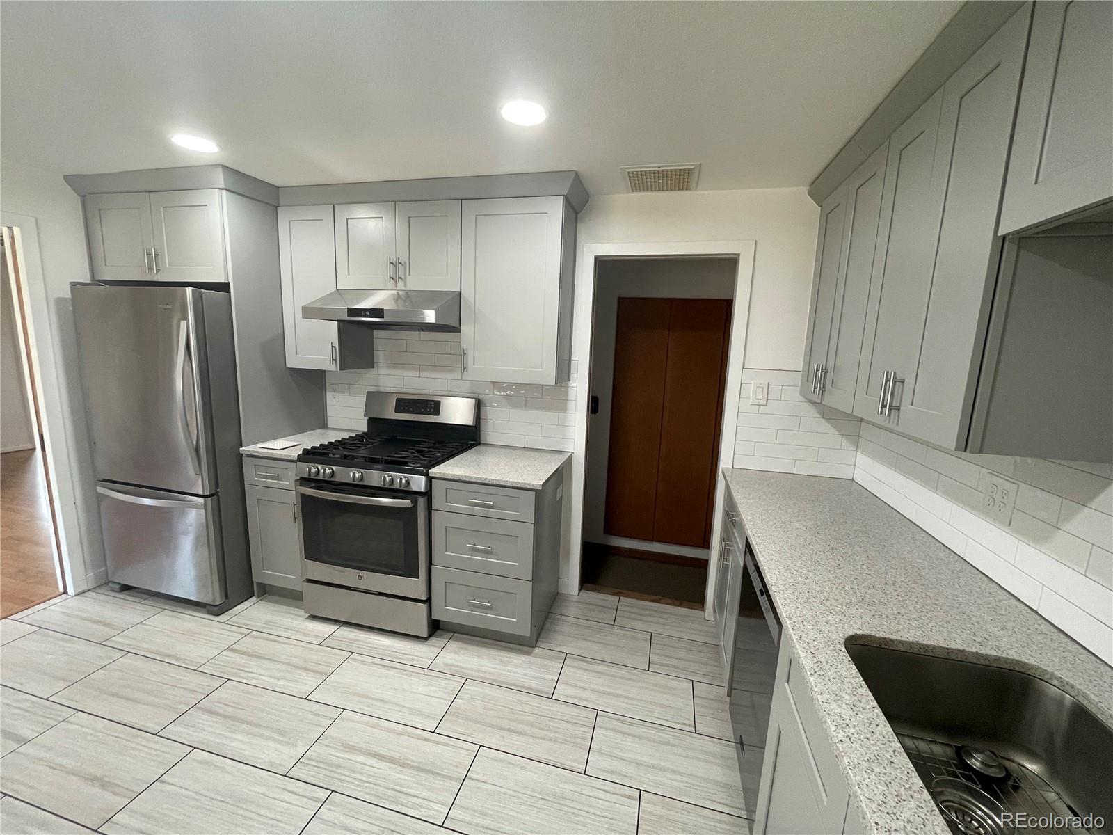 3086 Victor Street Aurora, CO 80011 - Photo 7 of 30 a kitchen with granite countertop a refrigerator and a stove top oven